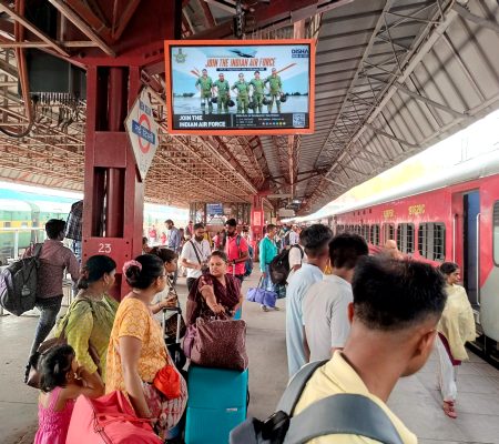 LED screen displaying an ad at a busy railway station platform, installed by Graphisads for high-impact outdoor visibility.